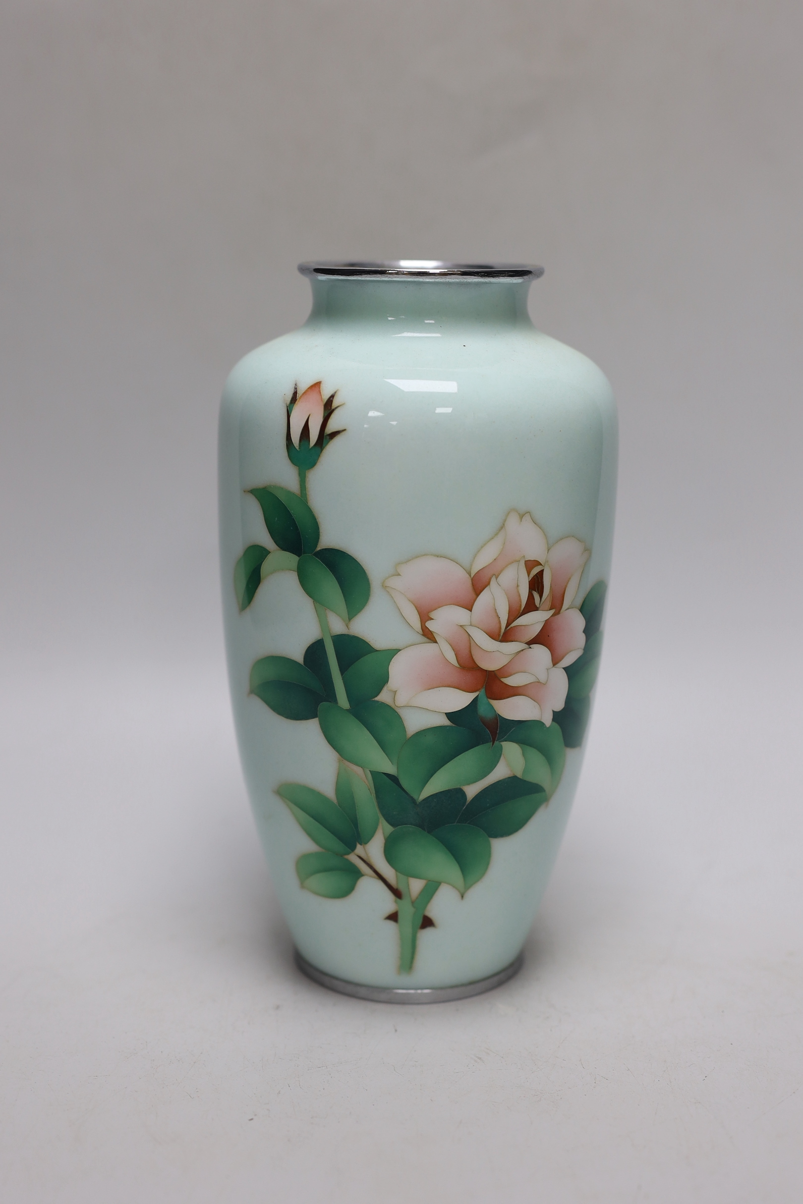 A Japanese cloisonné enamel vase decorated with roses upon a pale blue ground, silvered rim and base, 22cm high